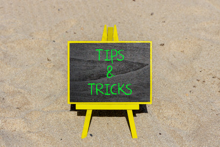 Tips and tricks words symbol. Concept words Tips and tricks on beautiful black blackboard. Beautiful sand beach background. Business tips and tricks motivational support concept. Copy space.