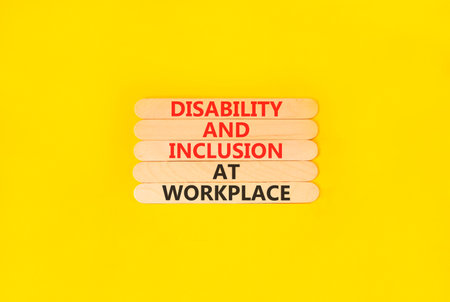 Disability and inclusion symbol. Concept words Disability and inclusion at workplace on beautiful wooden sticks. Beautiful yellow background. Disability and inclusion at workplace concept. Copy space.
