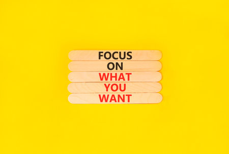 Focus on what you want symbol. Concept words Focus on what you want on beautiful wooden sticks. Beautiful yellow background. Psychological and focus on what you want concept. Copy space.