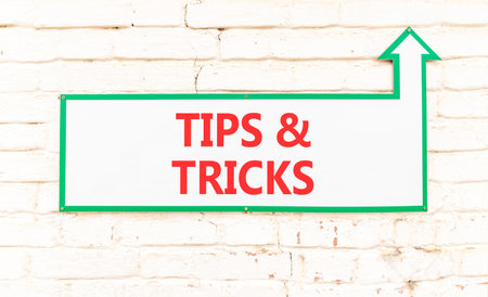 Tips and tricks words symbol. Concept words Tips and tricks on beautiful white sign plate. Beautiful white brick wall background. Business tips and tricks motivational support concept. Copy space.