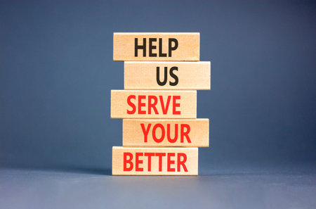 Help us serve you better symbol. Concept words Help us serve you better on beautiful wooden blocks. Beautiful grey background. Business and help us serve you better concept. Copy space.