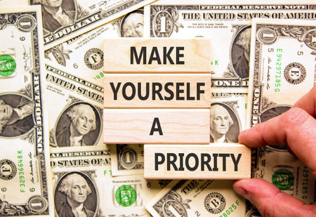 Make yourself a priority symbol. Concept words Make yourself a priority on beautiful wooden blocks. Beautiful dollar bills background. Business psychological make yourself priority concept. Copy space