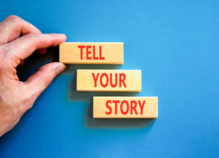 Tell your story symbol. Concept word Tell your story on beautiful wooden blocks. Beautiful blue table blue background. Businessman hand. Business tell your story concept. Copy space.
