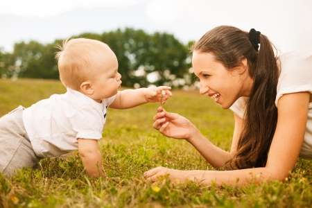 mother passing flower to her baby in the parkの写真素材