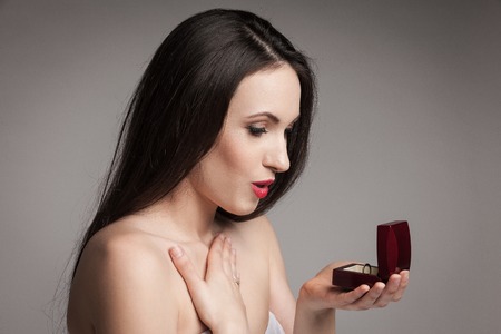 Surprised beautiful woman holding jewelry box with an engagement ring in it. Happy young woman after...