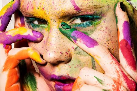 Close-up portrait of young woman with unusual makeup. Model posing with paint drops over her face. Creative makeup.の写真素材