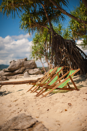 Deckchairs on a beautiful sandy beach with colorful nature on background. Vacation concept.の写真素材