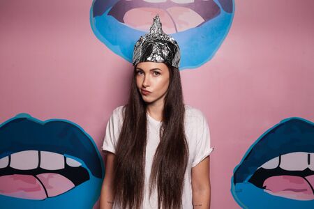Attractive young woman wearing tinfoil hat for protection. Conspiracy theory concept.