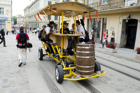 LVIV, UKRAINE - JUNE 13: Entertainment for the tourist, who came to the EURO-2012 on June 13, 2012 in Lviv, Ukraine. On photo - Cafe-velomobile in the centre of Lviv. It's really fun!のeditorial素材