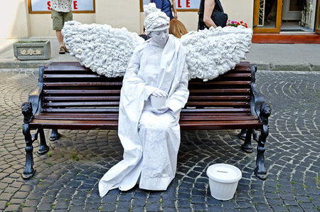 LVIV, UKRAINE - AUGUST 04, 2012: Entertainment for the tourist in centre of Lviv: Living statue - a woman in the image of a white angel.のeditorial素材