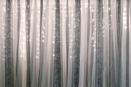 Translucent curtains adorned with electric garlandの写真素材