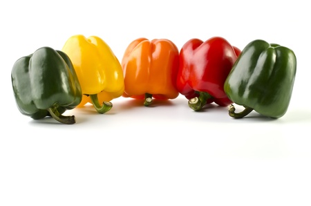 Five colorful peppers close-up arranged in a single line, isolated on a white backgroundの写真素材