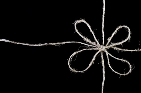 Bow made of twine close-up isolated on black backgroundの写真素材