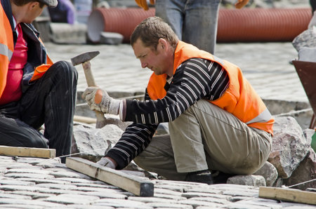 LVOV, UKRAINE - APRIL 25: Workers masons laid paving stones in the repair of the main street on April 25, 2013 in Lviv, Ukraineのeditorial素材