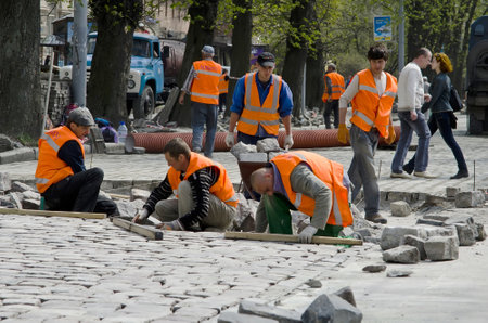 LVOV, UKRAINE - APRIL 25: Workers masons laid paving stones in the repair of the main street on April 25, 2013 in Lviv, Ukraineのeditorial素材