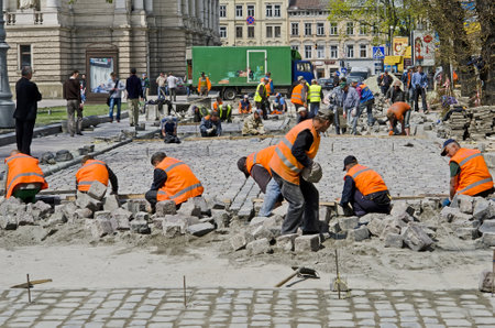 LVOV, UKRAINE - APRIL 25: Workers masons laid paving stones in the repair of the main street on April 25, 2013 in Lviv, Ukraineのeditorial素材