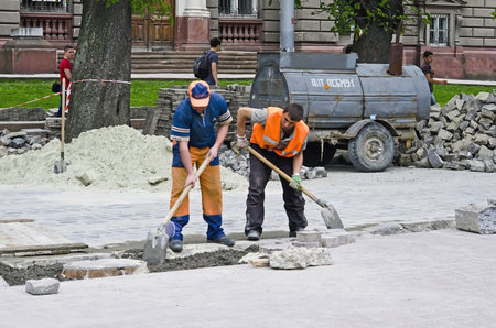 LVOV, UKRAINE - APRIL 27: Workers repairing the road during the repair on the main street of Lvov on April 27, 2013 in Lviv, Ukraineのeditorial素材