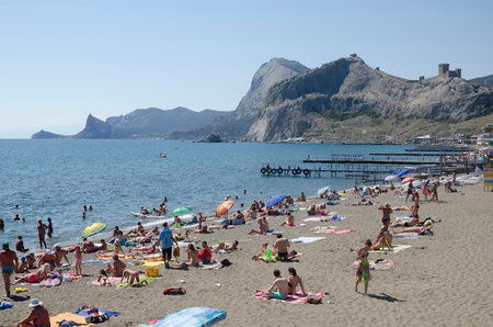 SUDAK, CRIMEA, RUSSIA - AUGUST 24: Tourists resting on the beach on august 24, 2014 in Sudak, Crimea, Russiaのeditorial素材