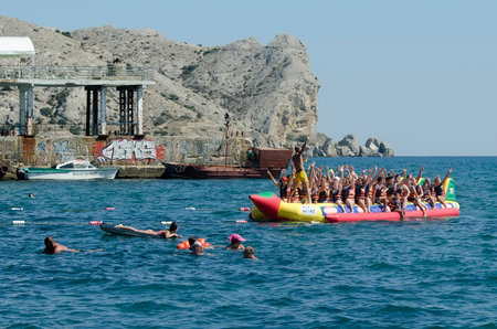 SUDAK, CRIMEA, RUSSIA - AUGUST 24: Attraction on the water - riding on water banana in Sudak on august 24, 2014 in Sudak, Crimea, Russiaのeditorial素材