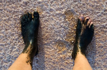 Feet covered with a black mud at salt lakeの写真素材