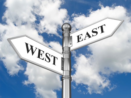Directional sign East West in the form of arrows on a background of cloudsの写真素材