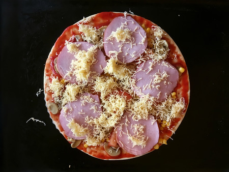 Delicious pizza with ham, tomato, mushrooms, cheese closeup on black backgroundの写真素材