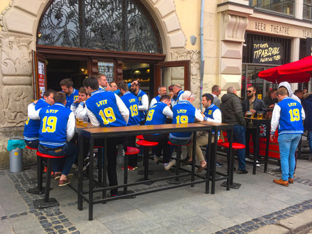 LVIV, UKRAINE - APRIL12: Fans of the Lviv football club in the same T-shirts drink beer in a street cafe in the center of Lviv on April 12, 2019 in Lvov, Ukraineのeditorial素材
