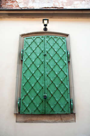 Antique green wrought iron shutters and street lamp in the center of Lviv