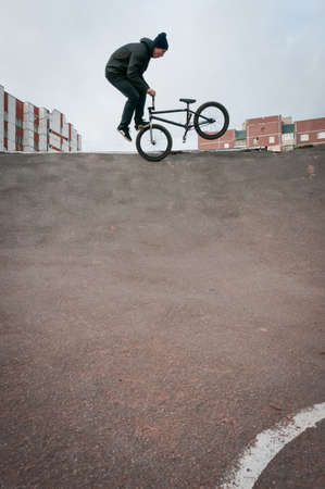 Biker doing footjam tailwhip trick with houses on backgroundの写真素材