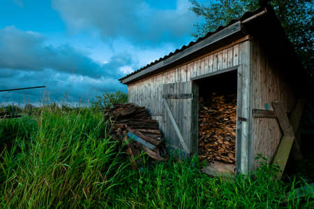 Old and hand made barn for firewood with grass and beautiful cloudscapeの写真素材