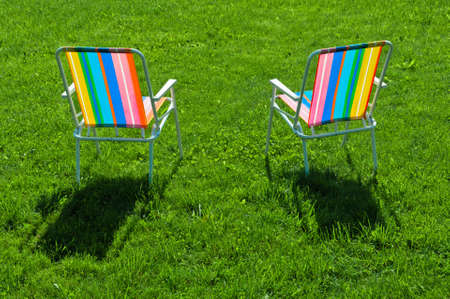 Two colorful chairs standing on grass at back yardの写真素材