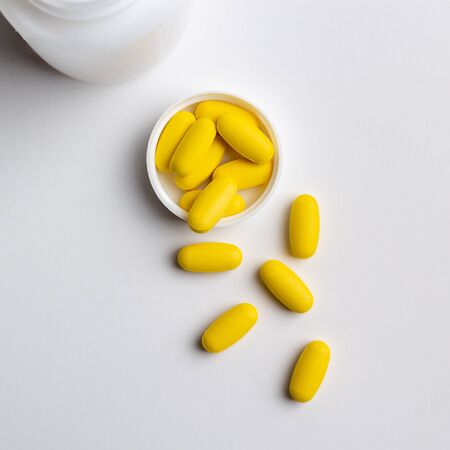 yellow pills and bottle isolated on white backgroundの写真素材