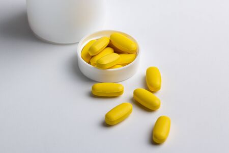 yellow pills isolated on white backgroundの写真素材