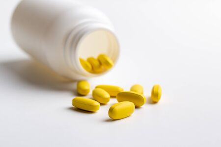 yellow pills and bottle isolated on white backgroundの写真素材