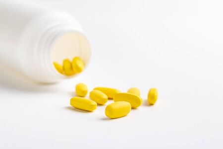 yellow pills and bottle isolated on white backgroundの写真素材