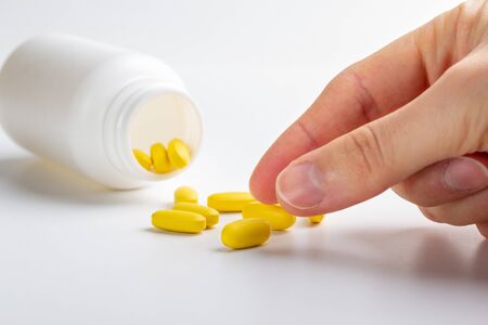 yellow pills and hand isolated on white backgroundの写真素材