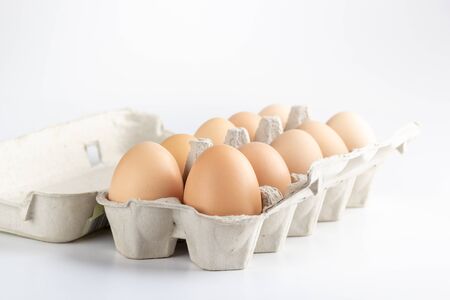 chicken eggs in a cardboard tray on white backgroundの写真素材