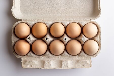 chicken eggs in a cardboard tray on white backgroundの写真素材