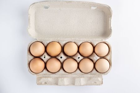 chicken eggs in a cardboard tray on white backgroundの写真素材