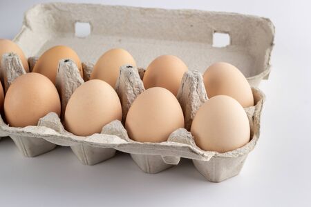 chicken eggs in a cardboard tray on white backgroundの写真素材