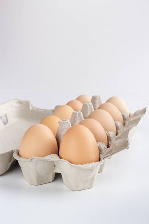 chicken eggs in a cardboard tray on white backgroundの写真素材