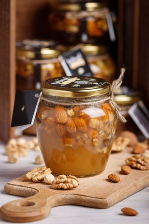 Jar of honey on a wooden board. Honey with nuts.の写真素材