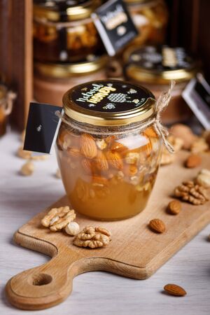 Jar of honey on a wooden board. Honey with nuts.の写真素材