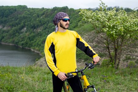 A cyclist sits on a bicycle and looks into the distanceの写真素材