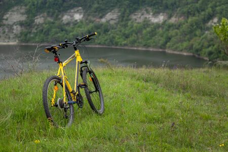 Yellow bicycle on green grass by the riverの写真素材