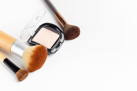 Makeup brushes of different sizes and makeup powder on a white backgroundの写真素材