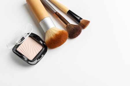 Makeup brushes of different sizes and makeup powder on a white backgroundの写真素材