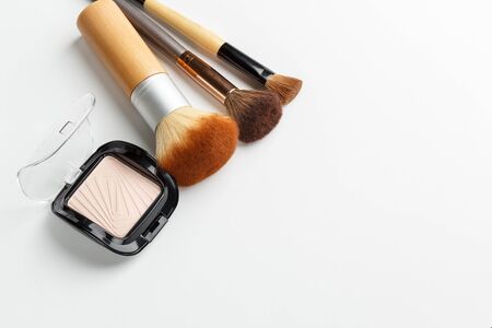 Makeup brushes of different sizes and makeup powder on a white backgroundの写真素材
