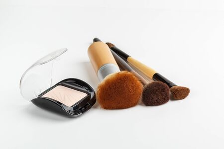 Makeup brushes of different sizes and makeup powder on a white backgroundの写真素材