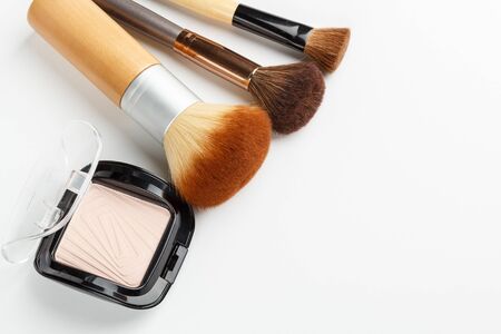 Makeup brushes of different sizes and makeup powder on a white background. Top view.の写真素材